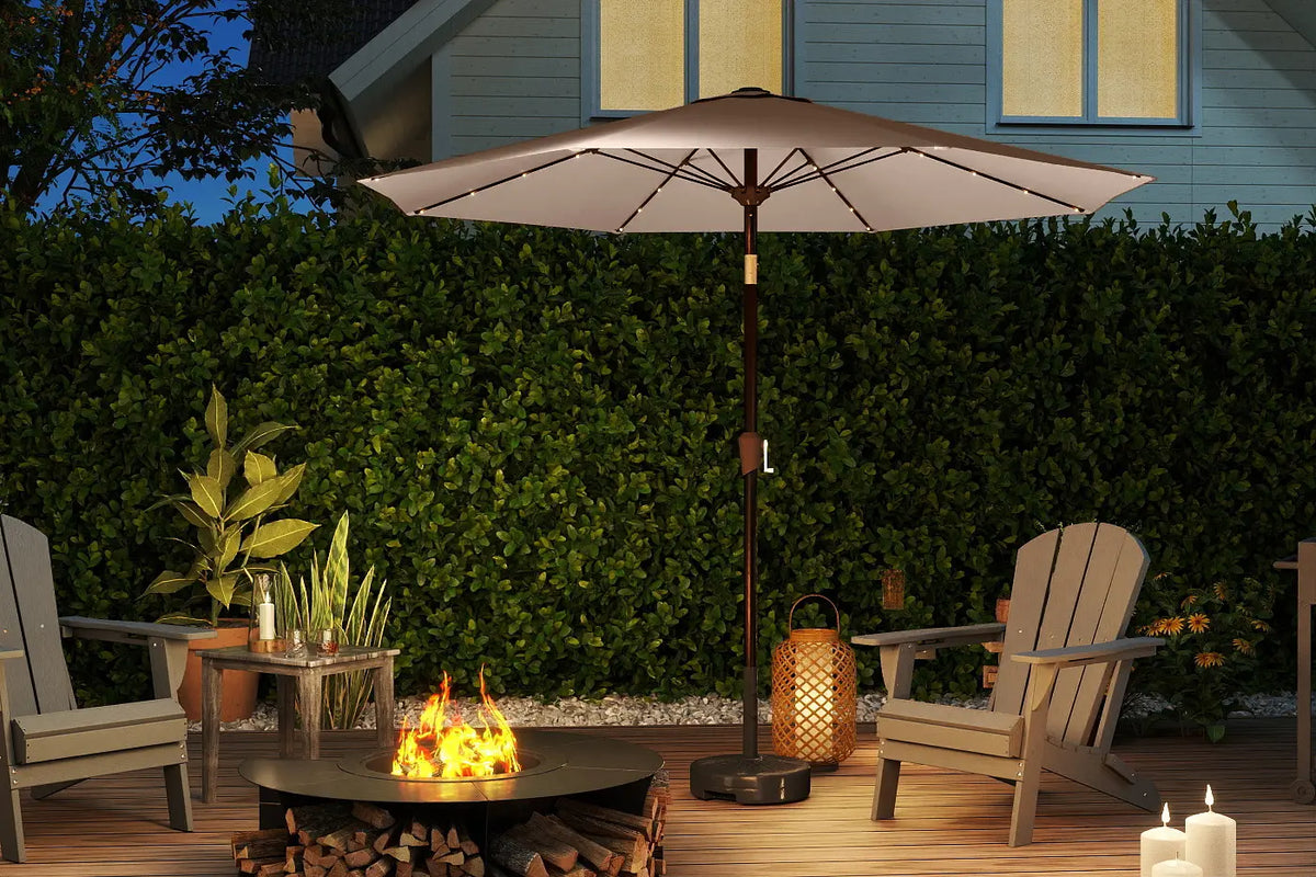Outdoor patio setting with a fire pit, chairs, and umbrella at night.