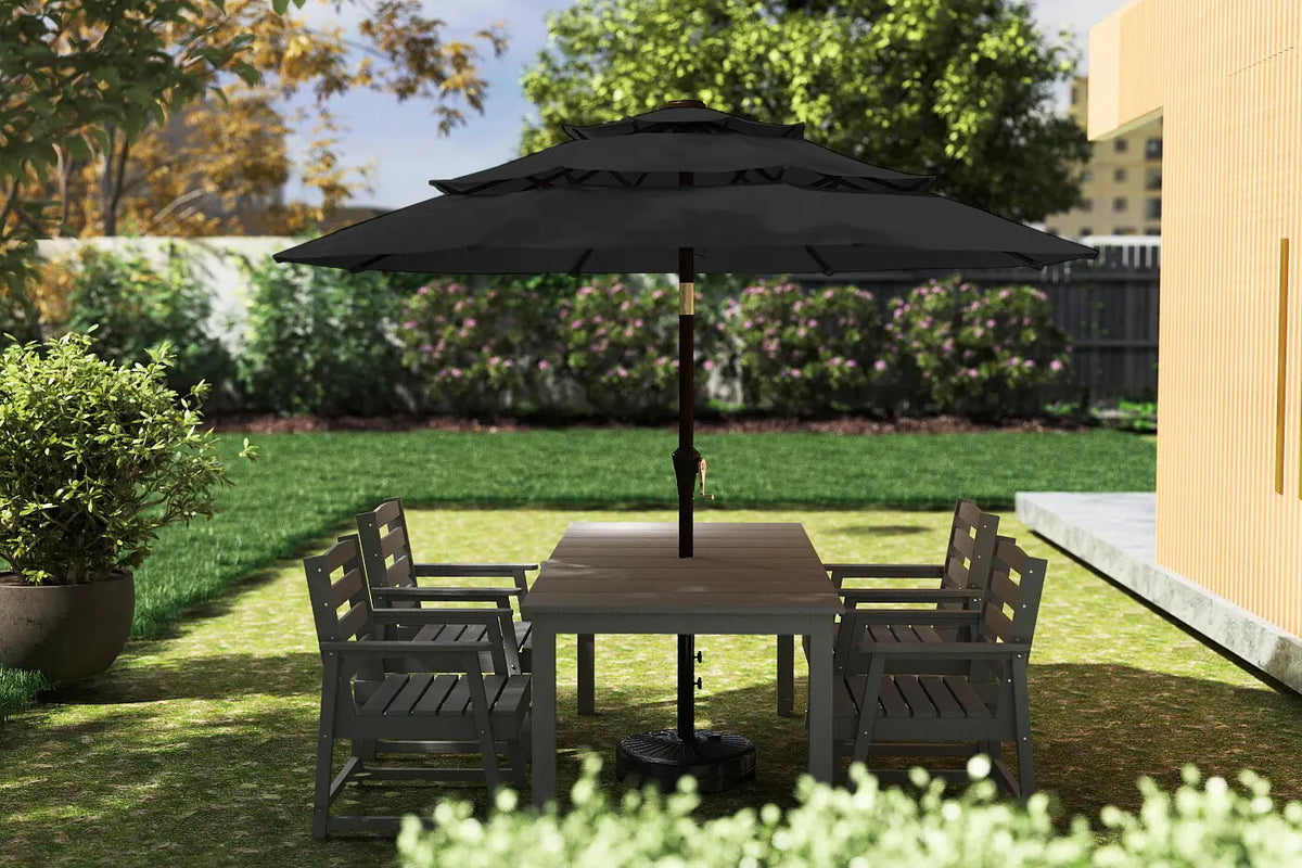 Outdoor patio set with table and chairs under a large black umbrella on a grassy area.