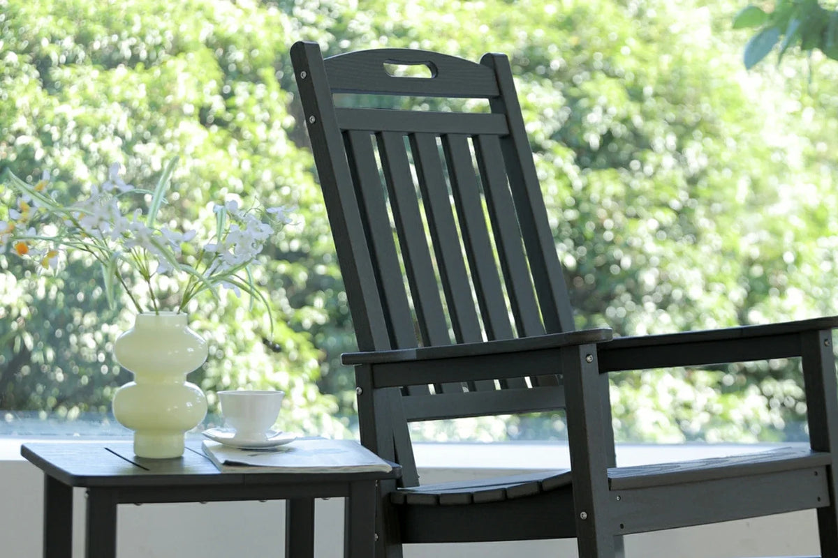 Black outdoor chair with a small table and decorative items on a blurred green background