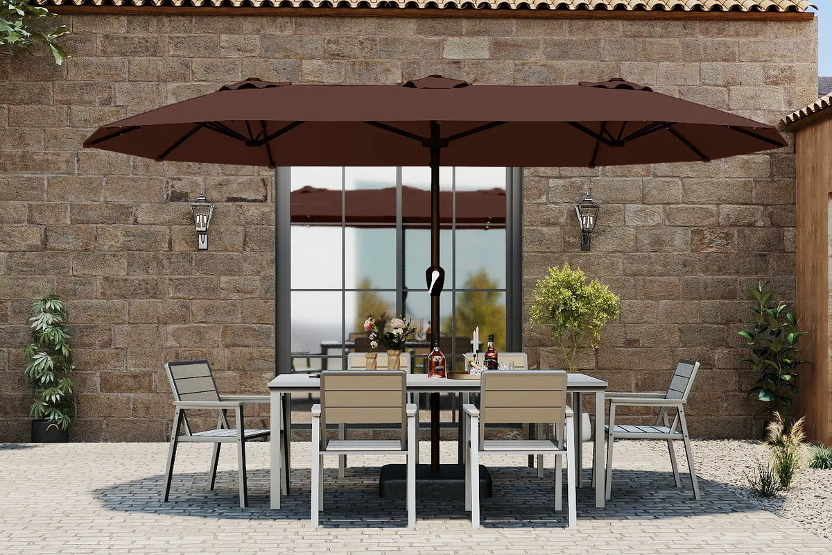 Outdoor dining set with large brown umbrella against a stone wall.