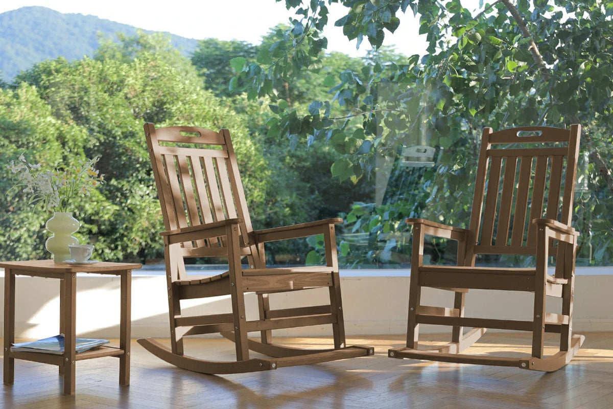 Two wooden rocking chairs on a patio with a scenic background
