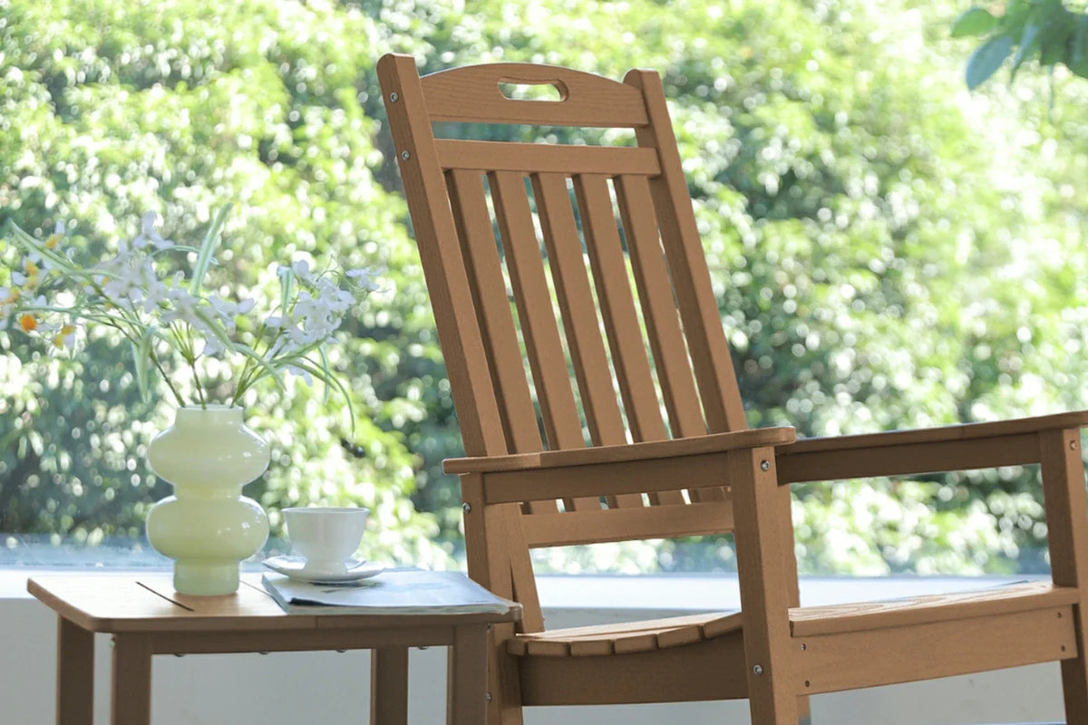 Wooden chair with a small table and decorative items on a blurred green outdoor background