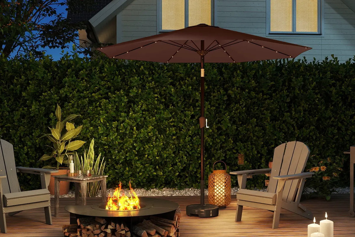 Outdoor patio setup with fire pit, chairs, and umbrella in a garden setting.