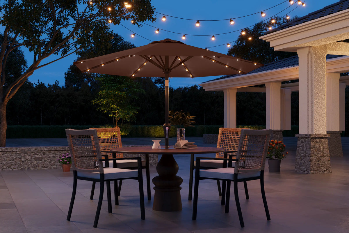 Outdoor patio setting with string lights, table, chairs, and umbrella at dusk.