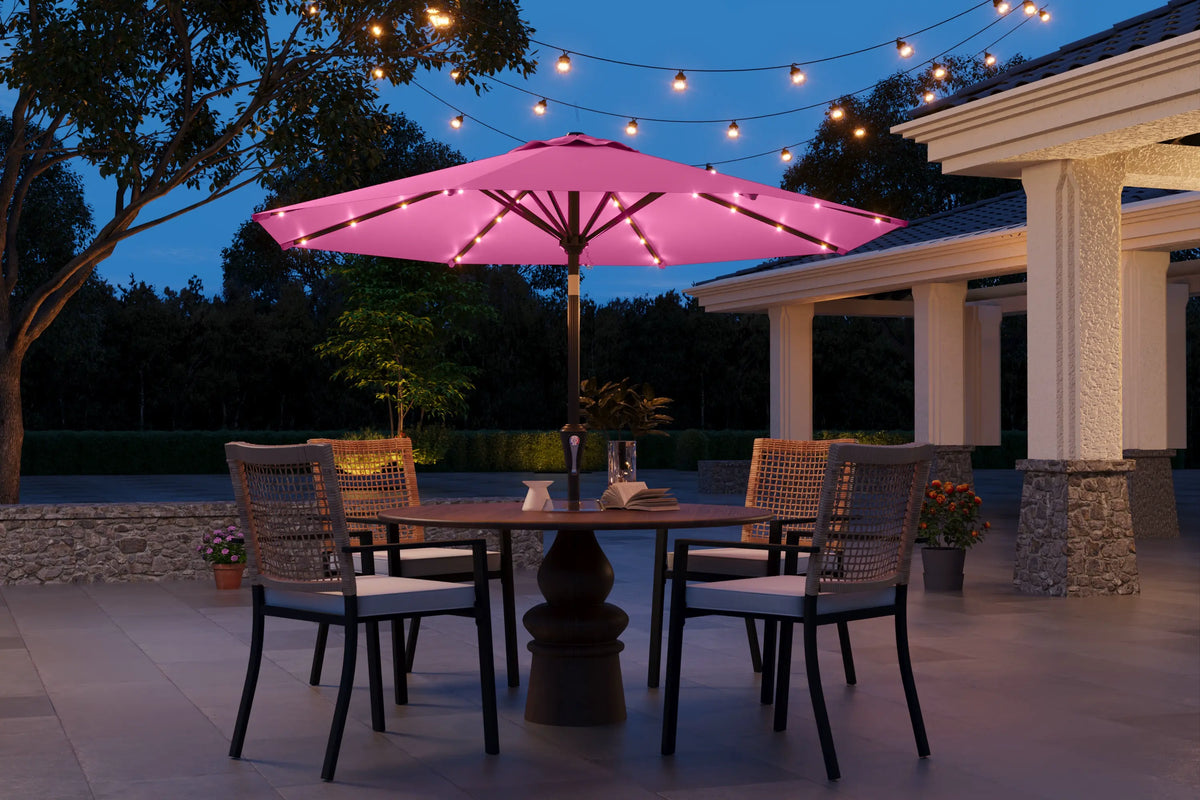 Outdoor patio setting with a pink umbrella and string lights at dusk.