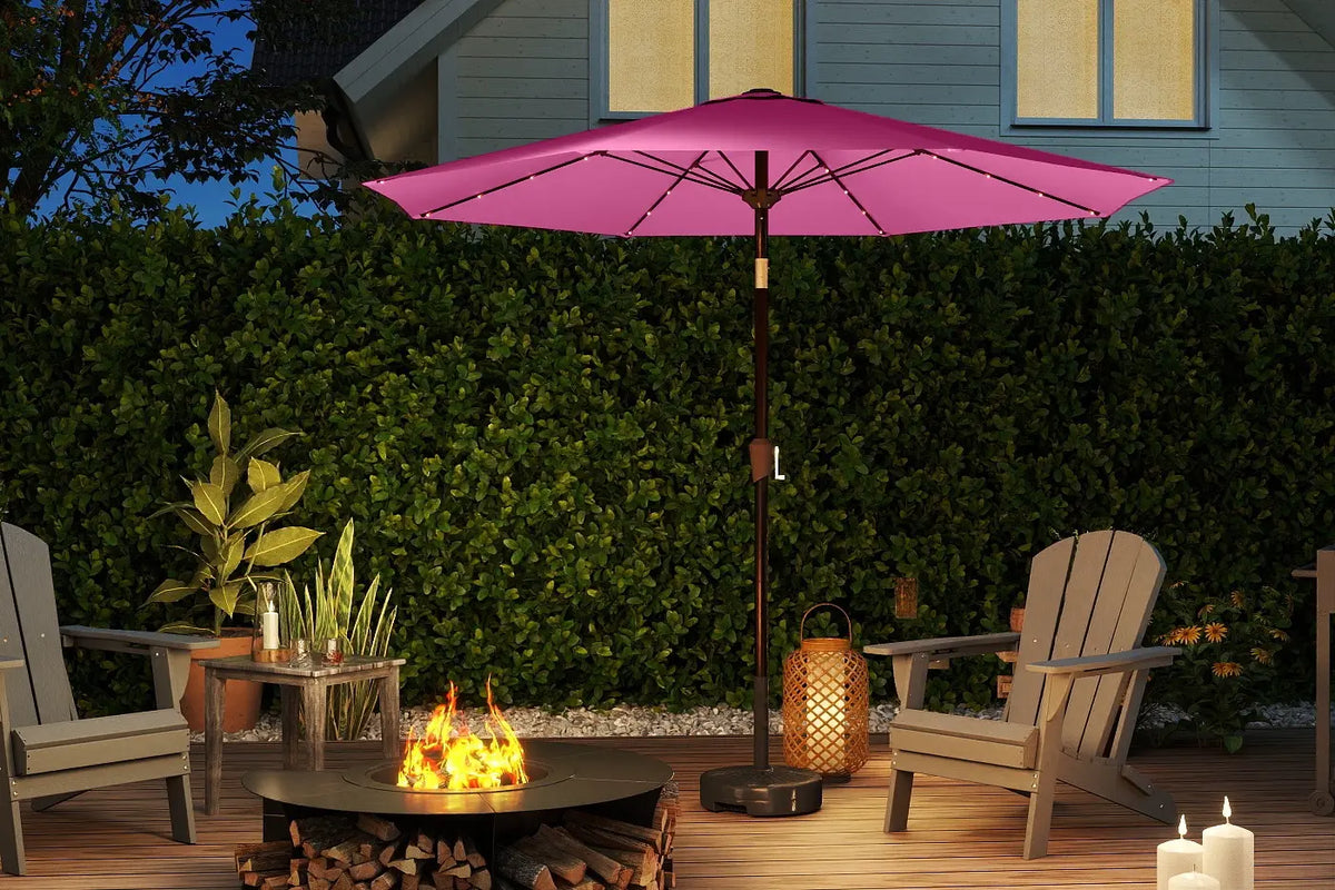 Pink patio umbrella over a fire pit with chairs and candles on a wooden deck.