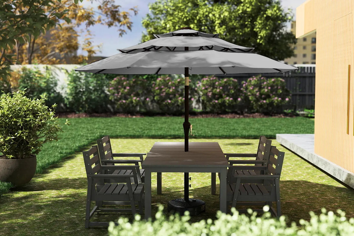Outdoor patio set with table and chairs under a large umbrella on a grassy area.
