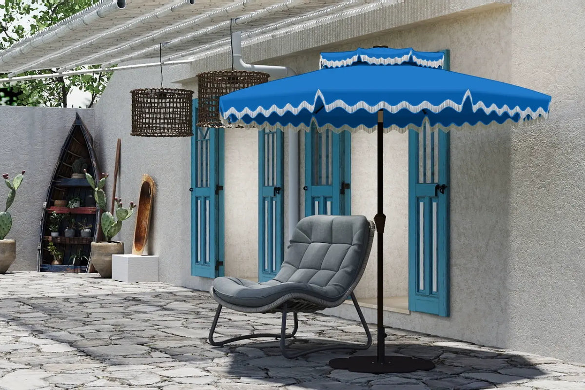Blue patio umbrella with white trim over a gray chair on a stone patio.