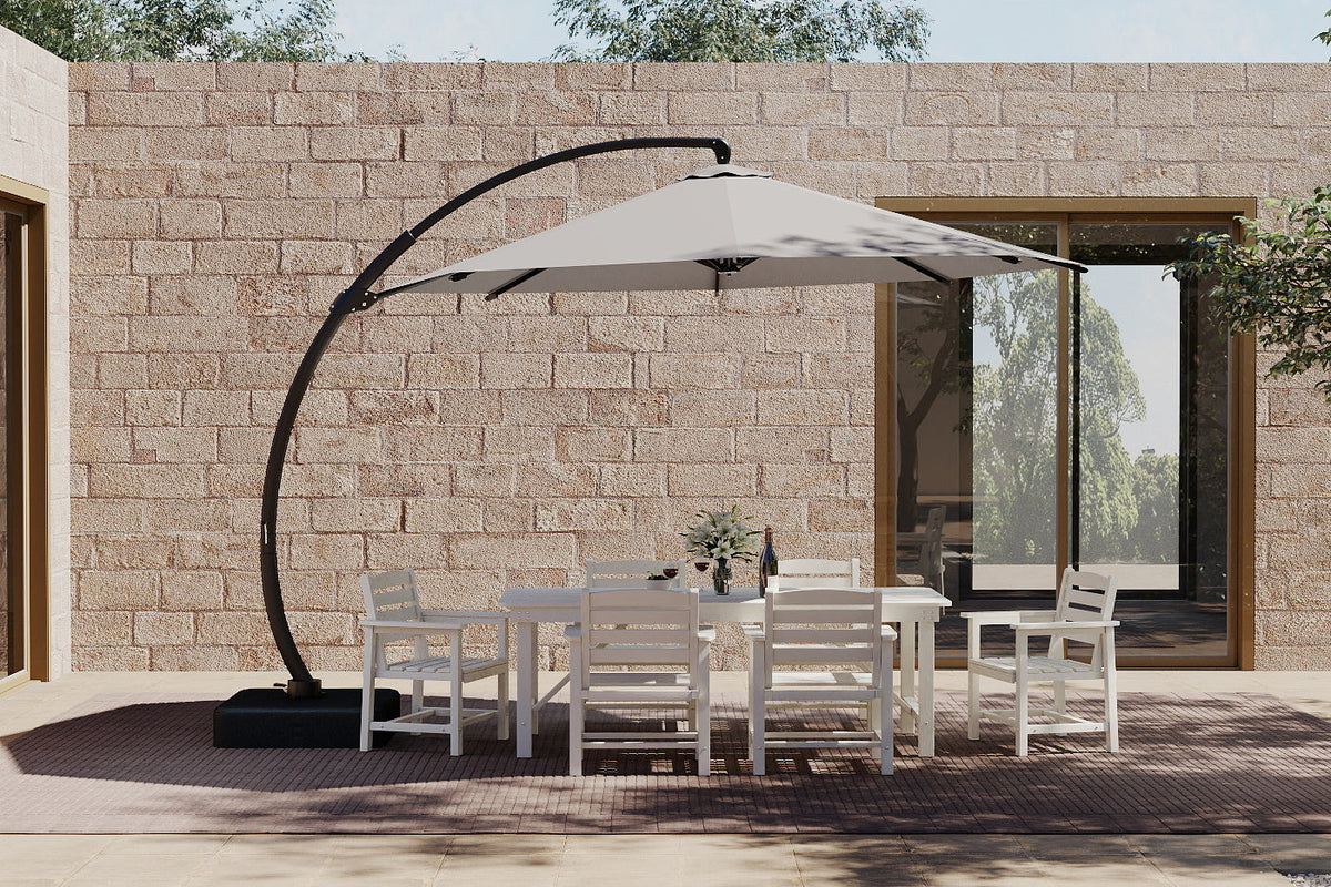 Outdoor patio set with table and chairs under a large patio umbrella against a stone wall.