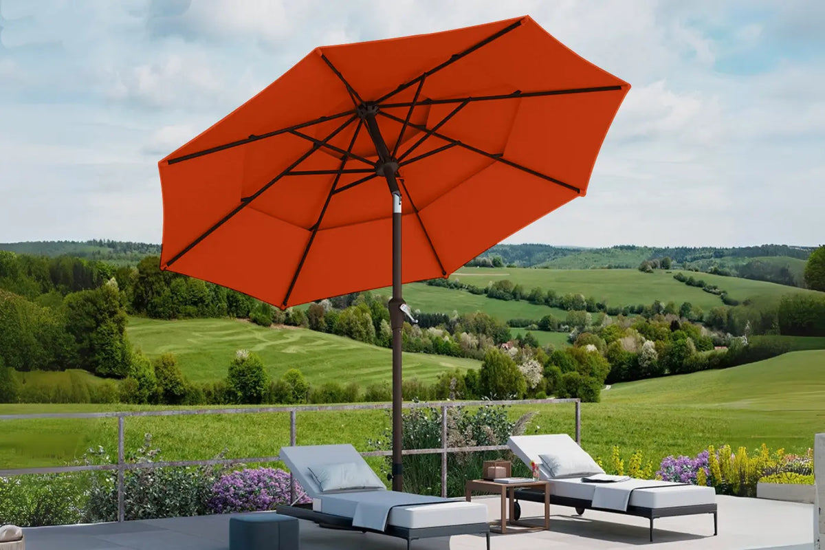 Orange patio umbrella with lounge chairs and a scenic view of green fields and hills.