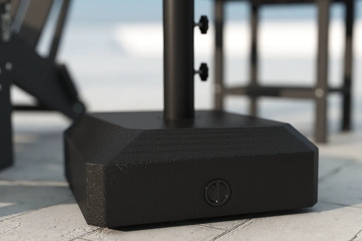 Black outdoor umbrella base on a patio with blurred background