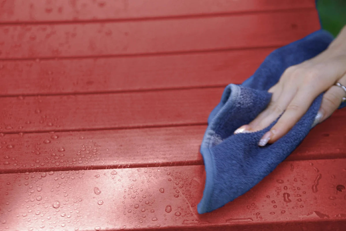 Person cleaning a red surface with a blue cloth