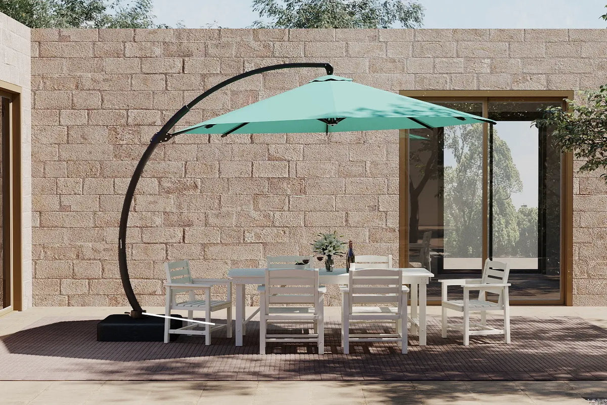 Outdoor patio set with a large green umbrella against a stone wall.