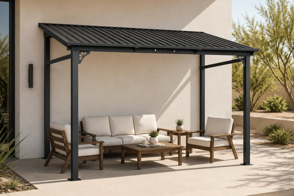 A wall-mounted hardtop gazebo with a slatted roof over a patio furniture set, including a wooden sofa, two armchairs, and a coffee table with white cushions, set against a beige stucco wall.