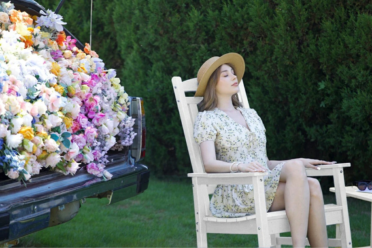 Woman sitting in a chair next to a car filled with flowers outdoors