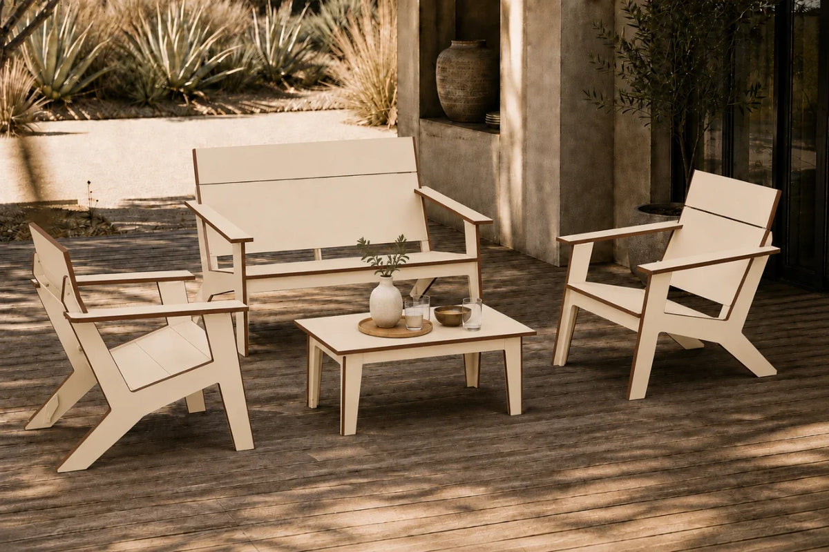 A four-piece outdoor patio furniture set including a loveseat, two armchairs, and a small coffee table, arranged on a wooden deck in a sunny patio setting.