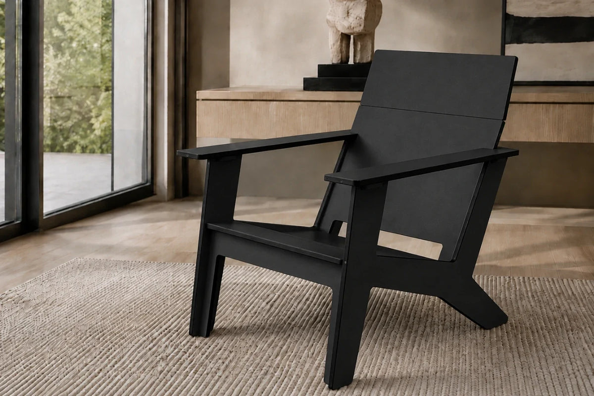 A modern black armchair with a wide armrest and angled legs, positioned on a textured beige rug in a contemporary indoor setting.
