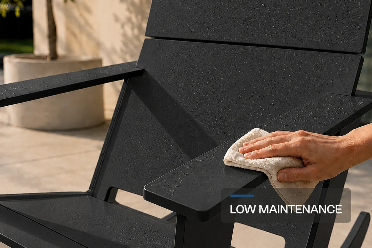 A close-up outdoor shot of a black Adirondack-style chair with water droplets on its surface, being wiped with a light beige cloth by a person's hand. The text 'LOW MAINTENANCE' is overlaid in the bottom right corner.