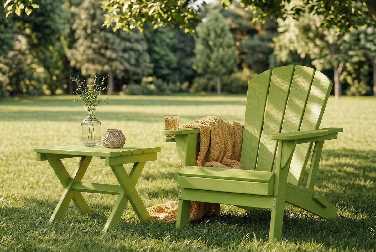 Green Adirondack chair and table set on a grassy lawn with trees in the background