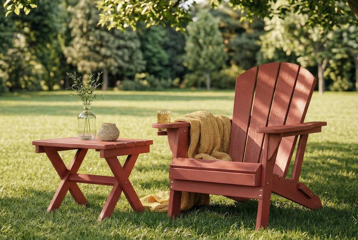 Red Adirondack chair and table set on a grassy lawn with trees in the background