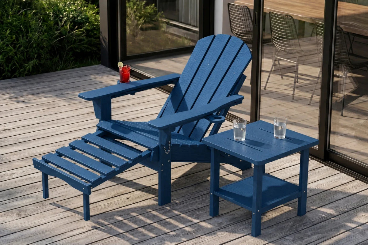 A navy blue outdoor Adirondack chair with an attached footrest and a matching side table on a wooden deck, with a glass drink on the table and a small red cup on the chair arm.