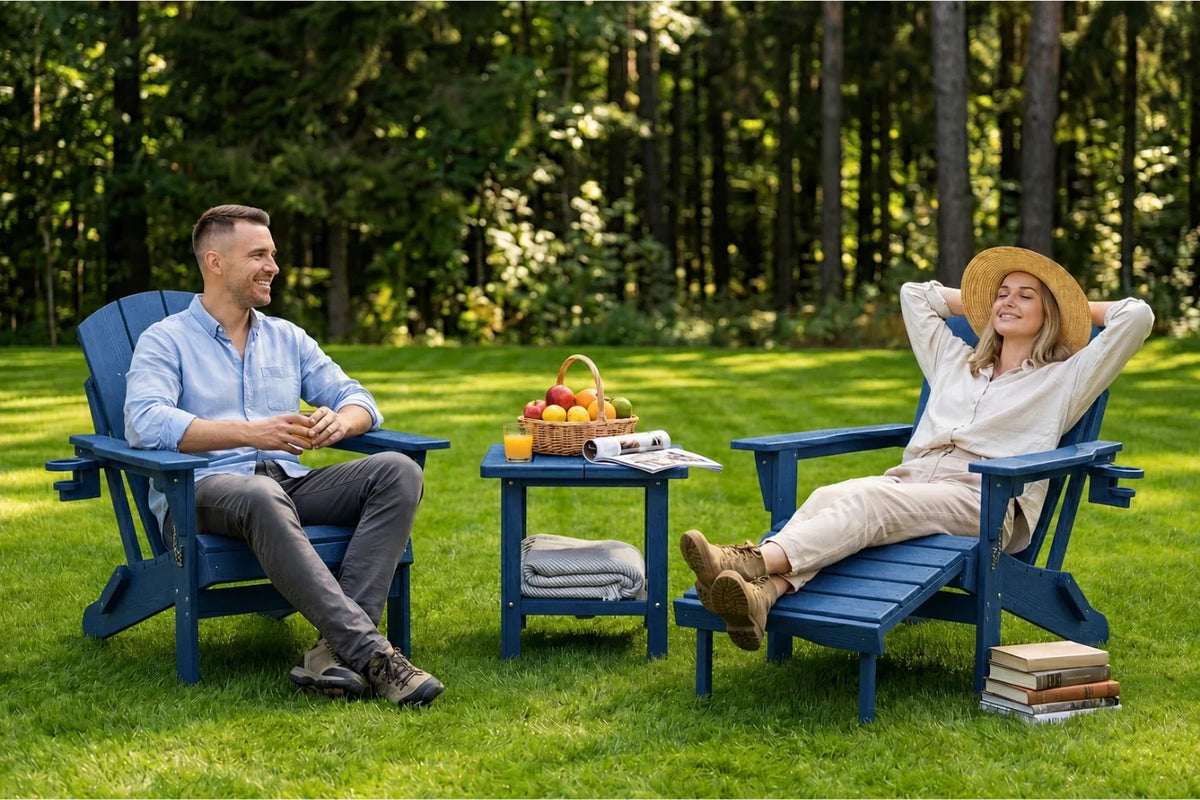 A man and a woman relax in navy blue Adirondack chairs on a grassy lawn with a small table between them, set against a backdrop of a dense green forest.