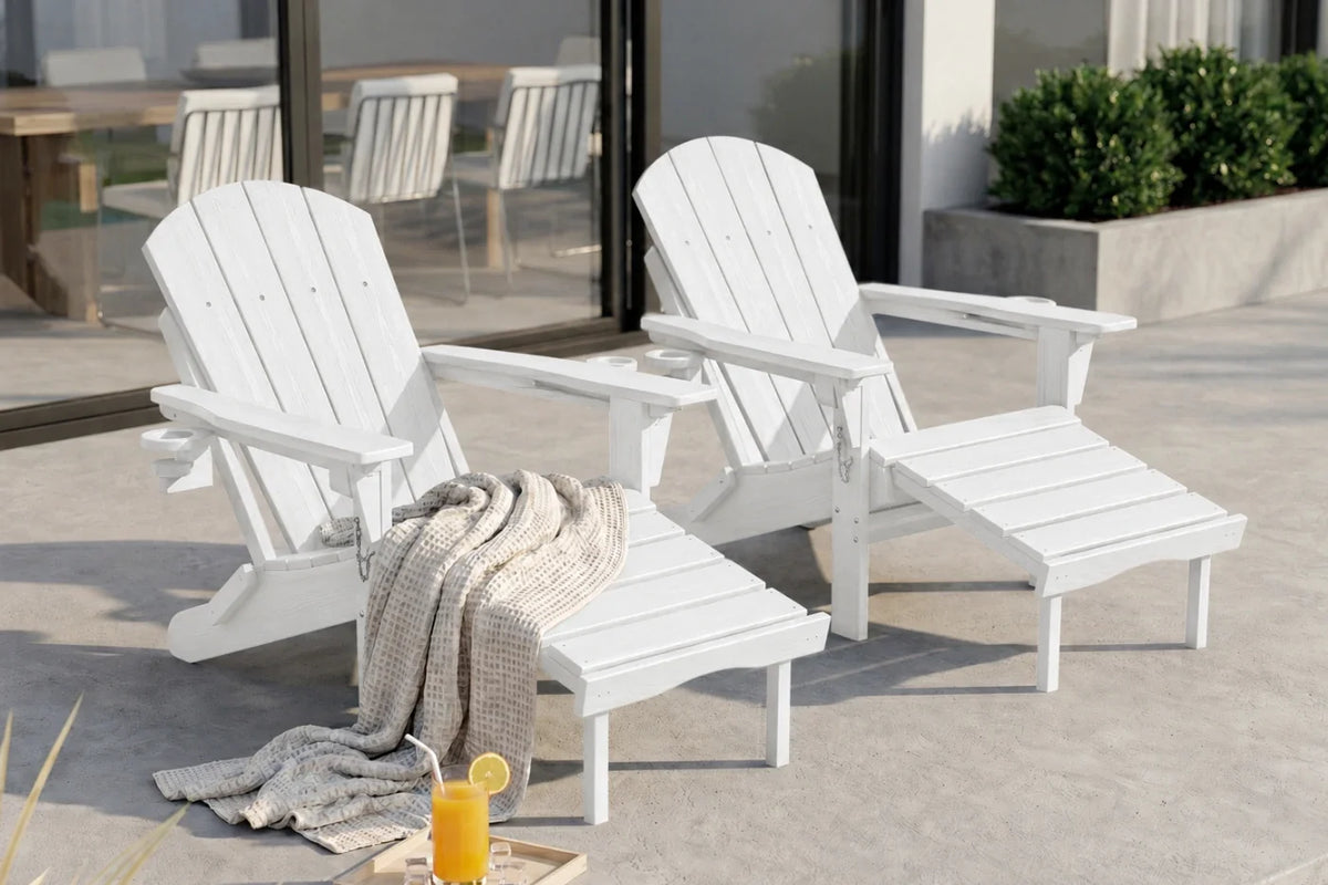 Two white outdoor Adirondack-style chairs on a patio, with a beige throw blanket draped over one chair and a glass of orange juice in the foreground.