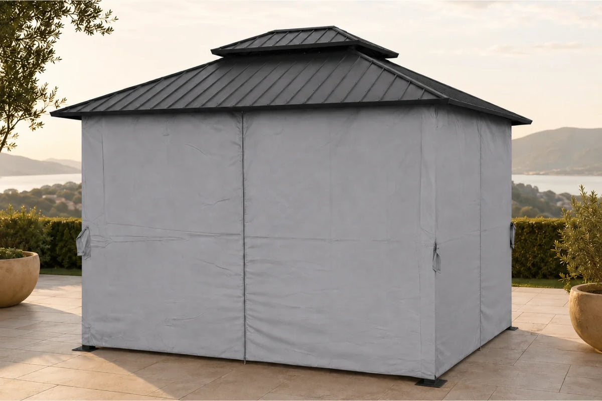 A gray outdoor patio gazebo with a dark gray metal double-tiered roof, set on a stone patio with a scenic lake and hills in the background.