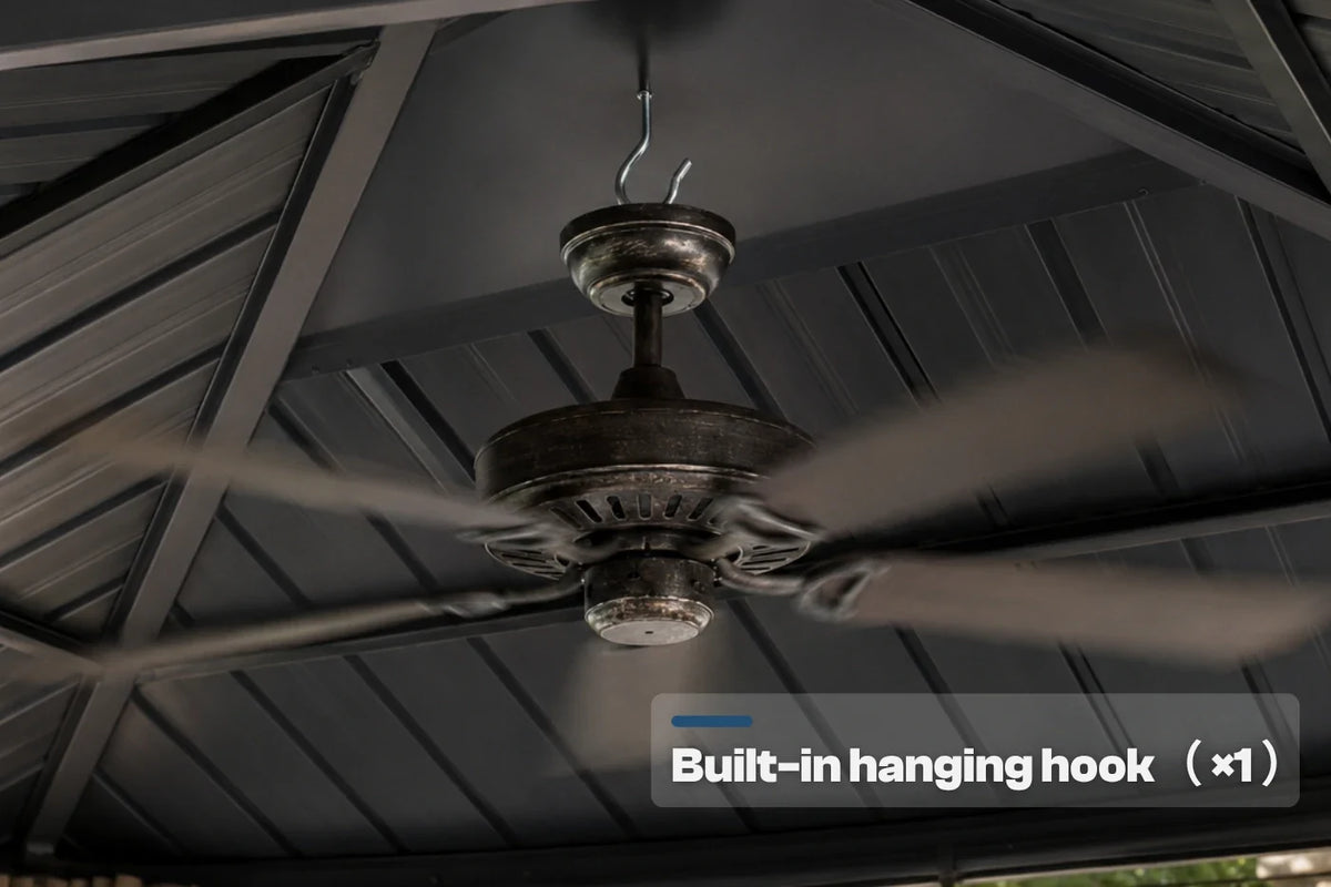 A dark metal three-blade ceiling fan hanging from a built-in hook under a dark gray metal patio roof. A text overlay at the bottom right reads 'Built-in hanging hook (x1)'.
