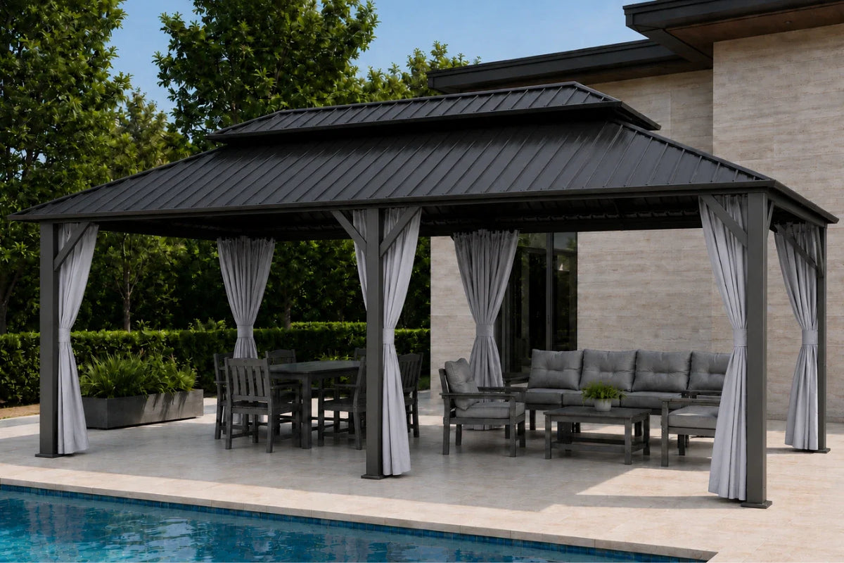 A dark gray hardtop gazebo with netting and curtains, sheltering a dining set and a lounge sofa on a poolside patio in front of a modern house.