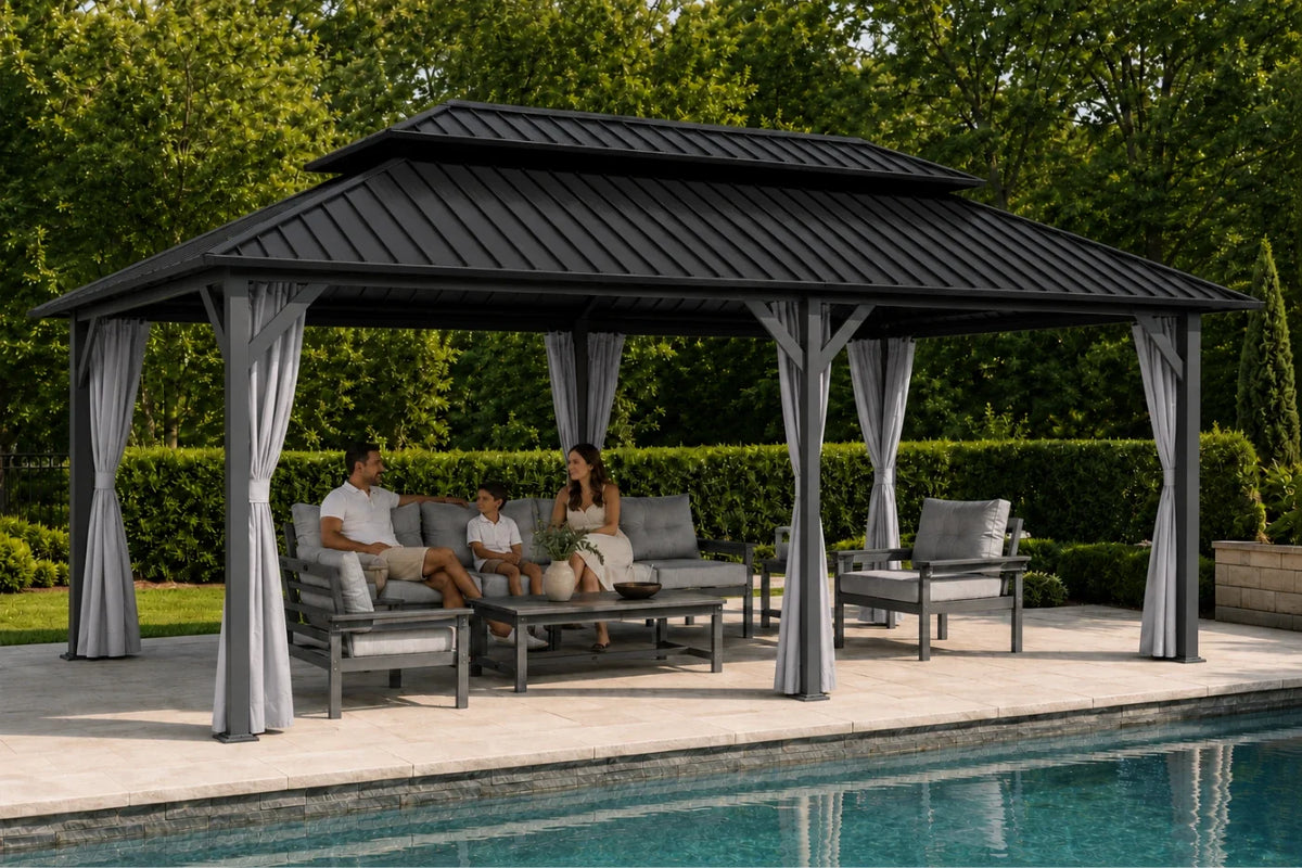A large dark gray double-tiered gazebo with gray curtains and a gray outdoor seating area, situated next to a swimming pool with people relaxing underneath.