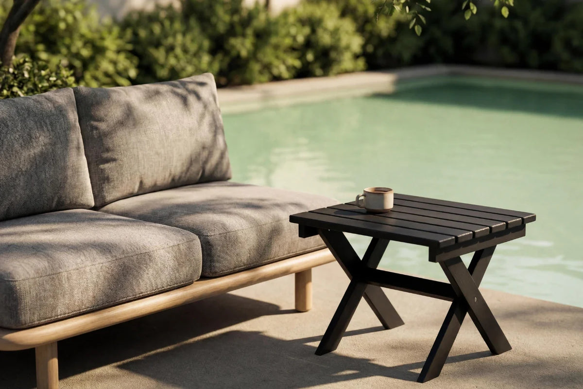 Outdoor patio set with gray sofa and black table by a pool