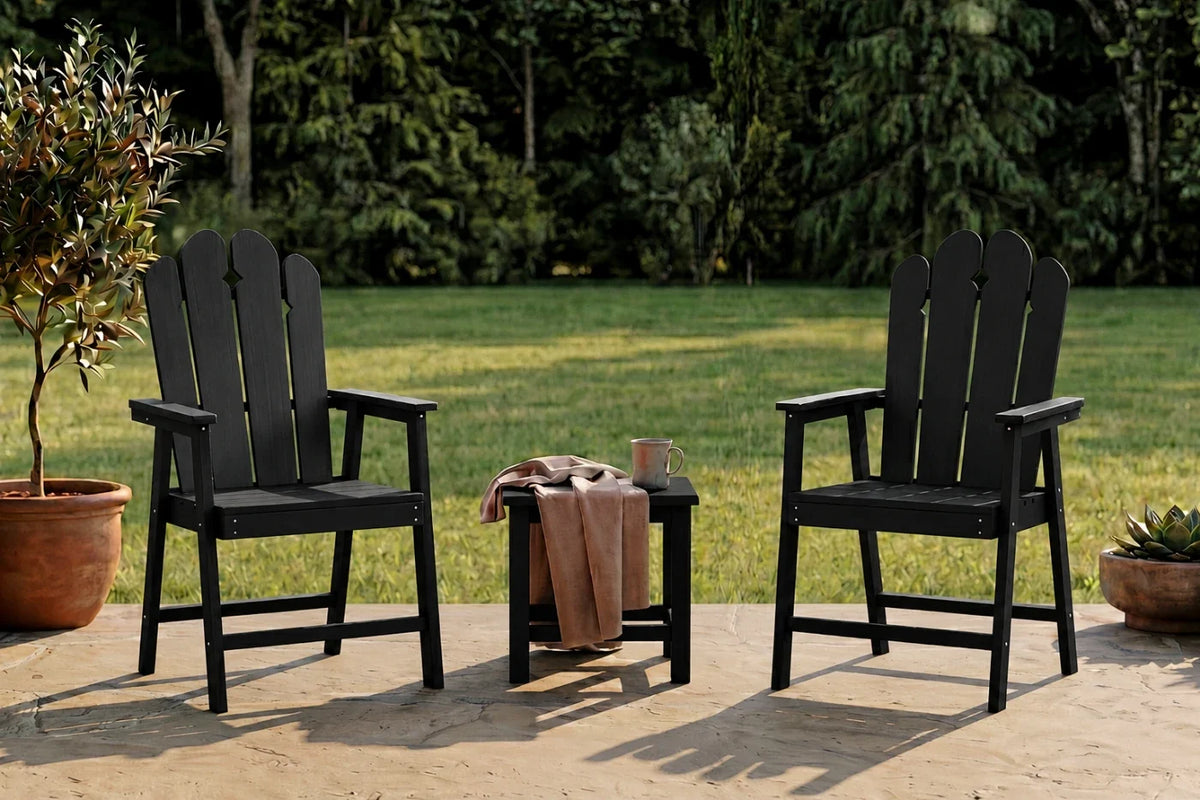 Two black HDPE chairs with a small table on a patio, surrounded by greenery.