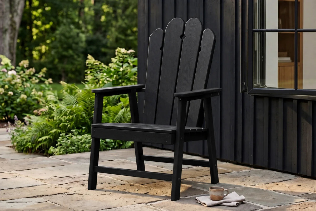 Black HDPE chair on a stone patio with greenery and a building in the background