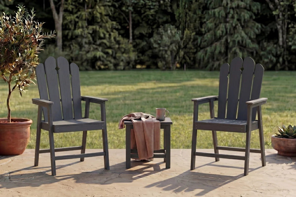 Two dark gray HDPE chairs with a small table on a patio with greenery in the background.