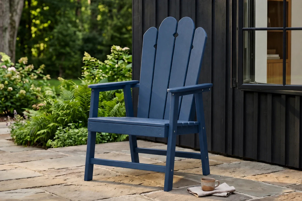 Navy blue HDPE chair on a stone patio with greenery and a building in the background