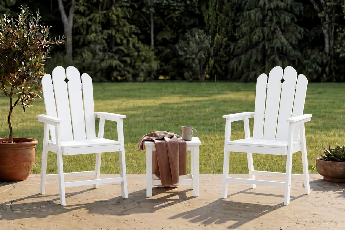 Two white HDPE chairs with a small table on a patio with greenery in the background.