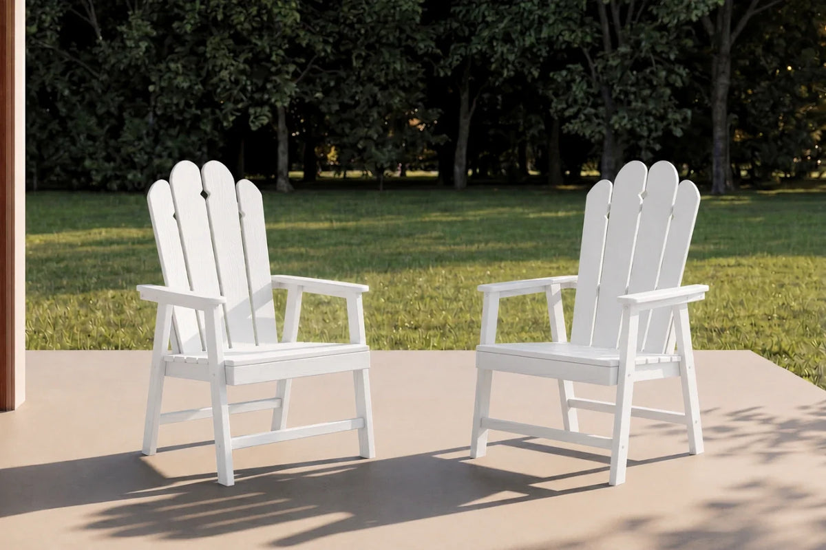 Two white HDPE chairs on a patio with green grass and trees in the background.