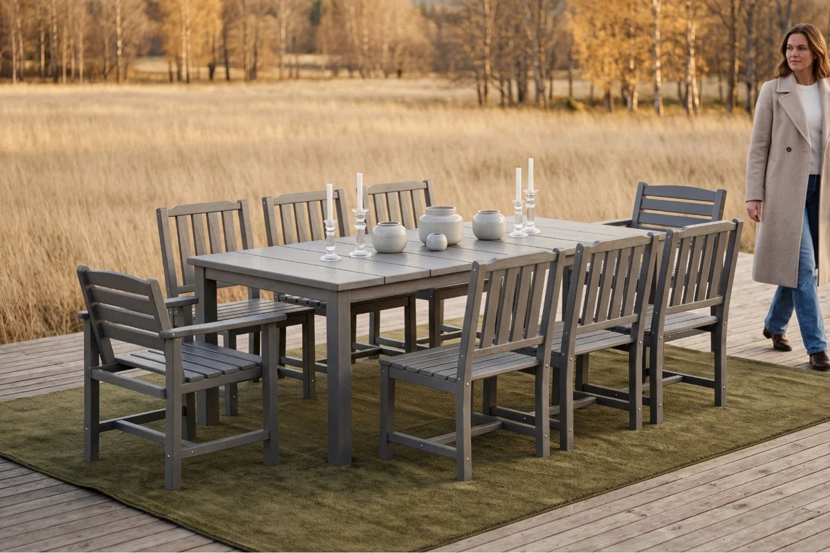 Outdoor dining set with table and chairs on a deck, woman in coat standing nearby.