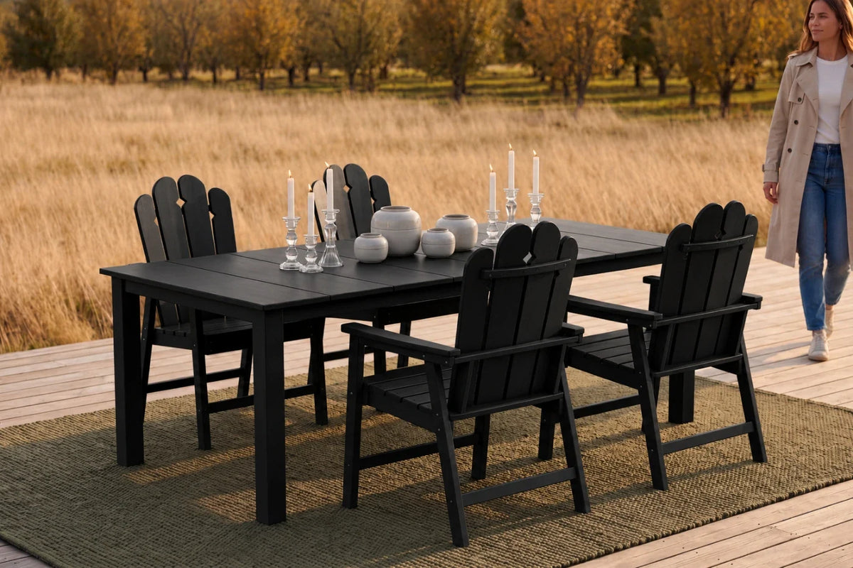 Black outdoor dining set with 4 chairs and table on a wooden deck, woman walking in the background.