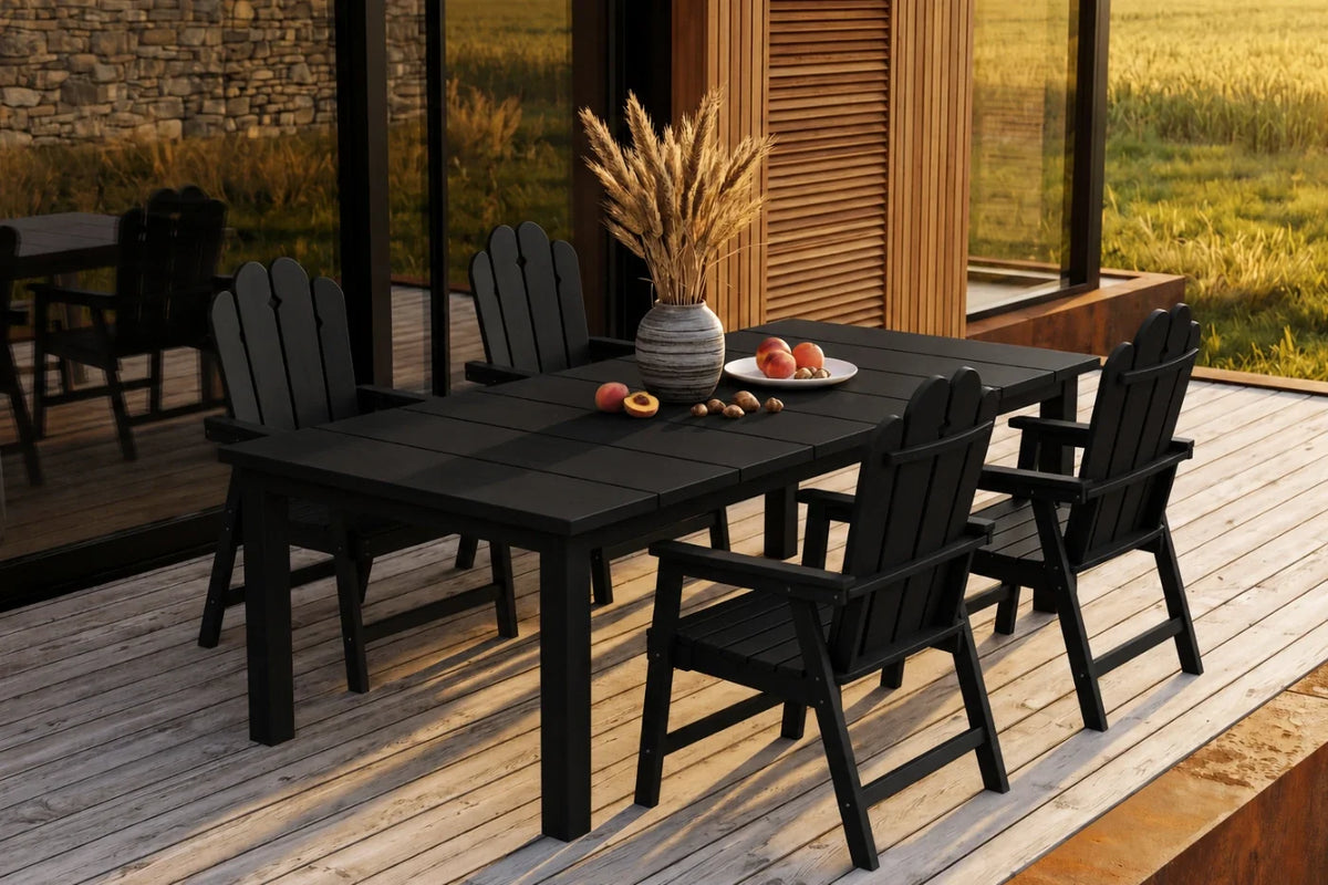 Black Outdoor dining set with table and 4 chairs on a wooden deck, featuring a stone wall and grassy field in the background.