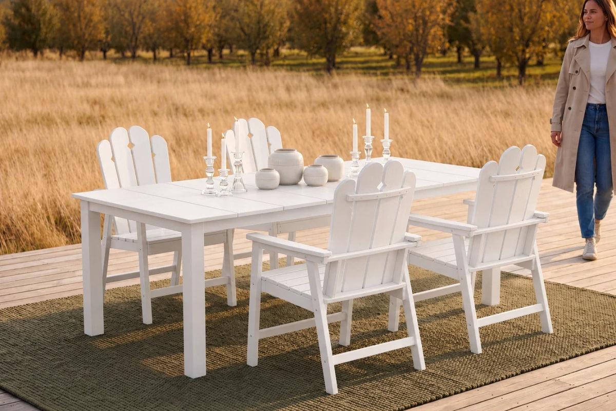 White outdoor dining set with candles on a wooden deck near a field