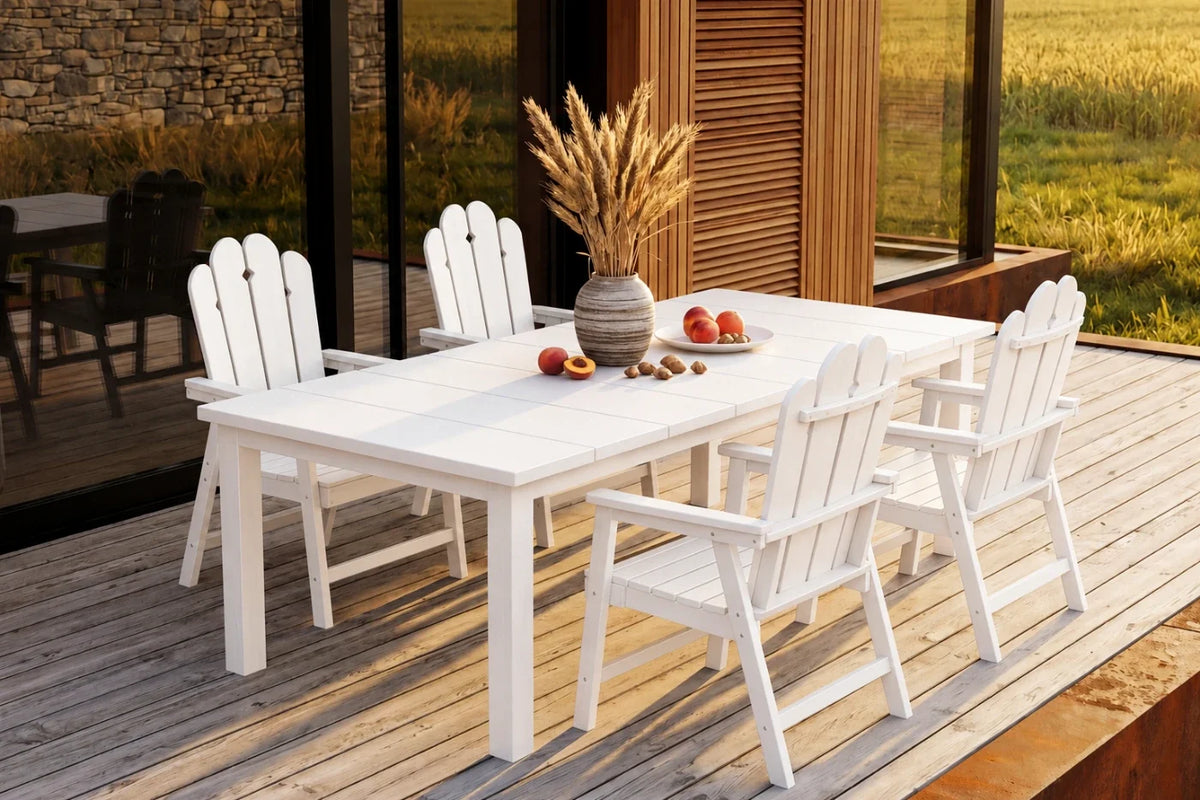 White outdoor dining table with chairs on a wooden deck, with a scenic background.