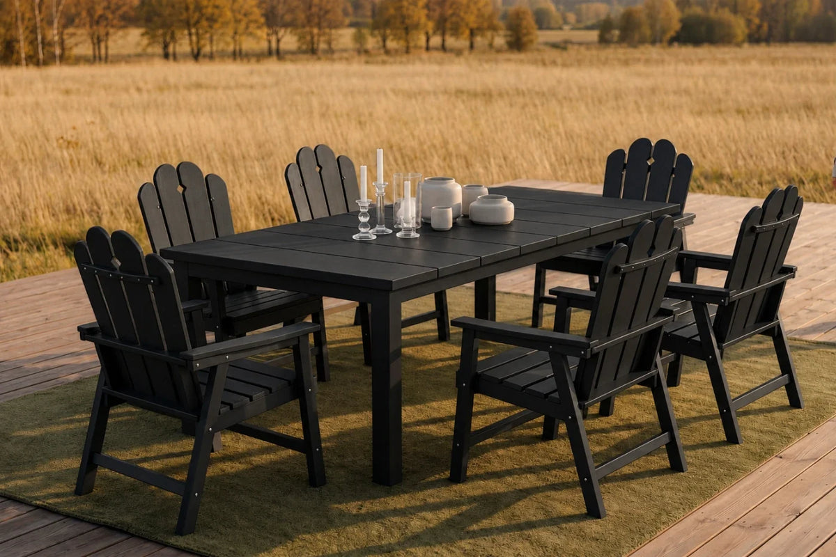 Outdoor dining set with black chairs and table on a grassy area with a field and trees in the background.