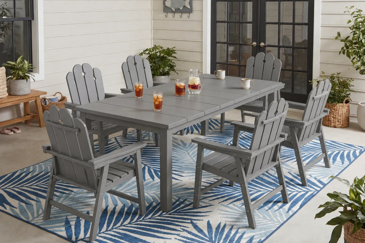 Gray Outdoor dining set with chairs and table on a patio with plants and a rug.