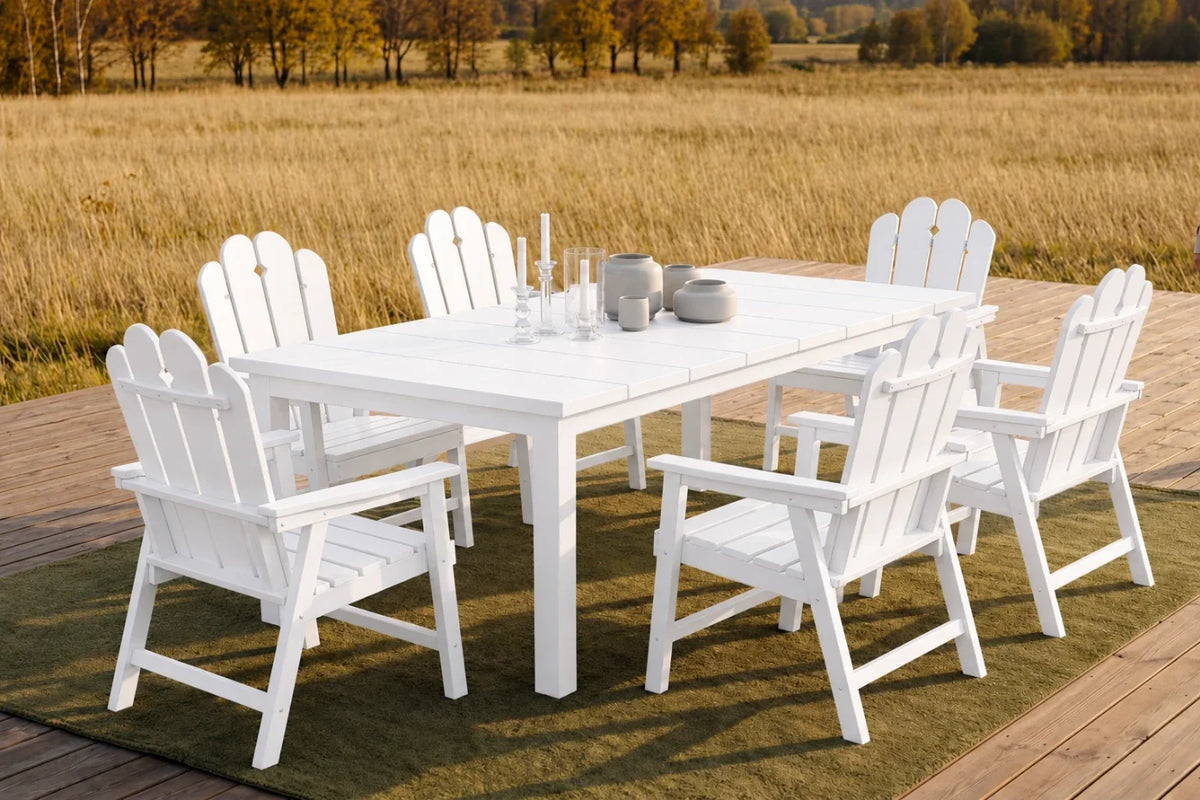 White outdoor dining set with chairs on a wooden deck overlooking a field.