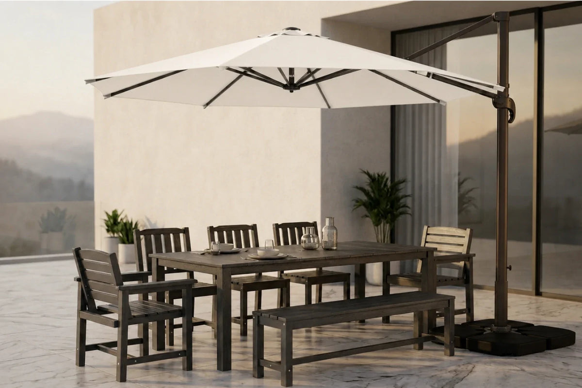 Outdoor patio dining set with a rectangular table, matching chairs and bench, and a large white cantilever umbrella on a tiled terrace beside a modern building.