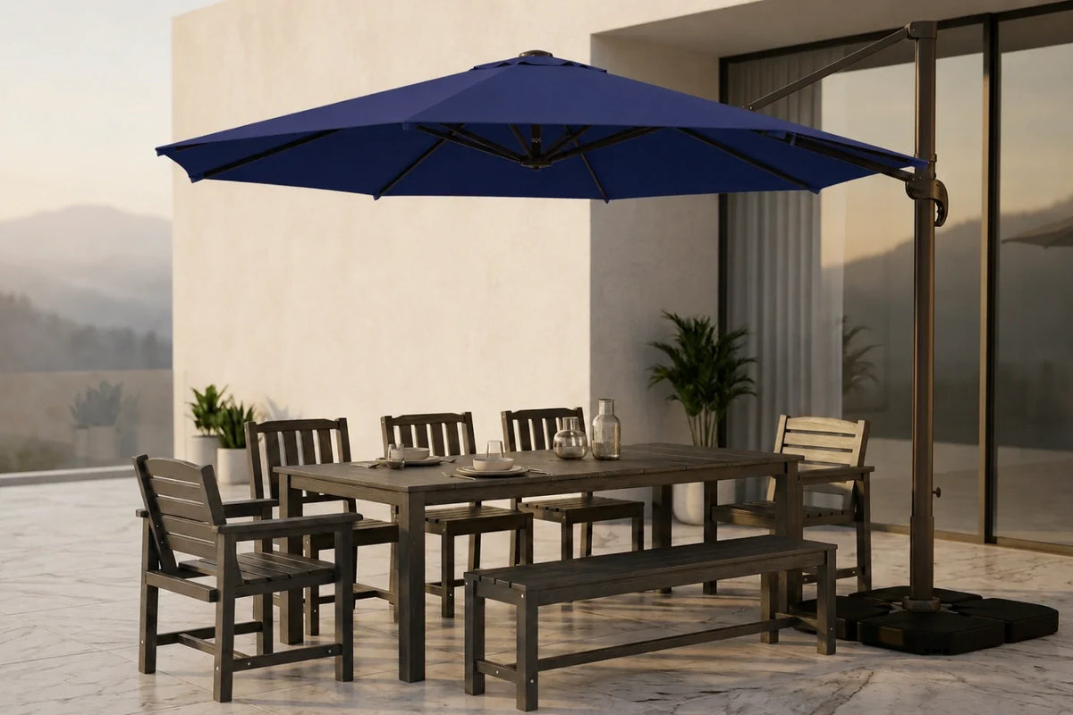 Outdoor patio dining set with a rectangular wooden table, matching bench, and six chairs under a large navy blue cantilever umbrella, staged on a tiled patio in front of a modern building.