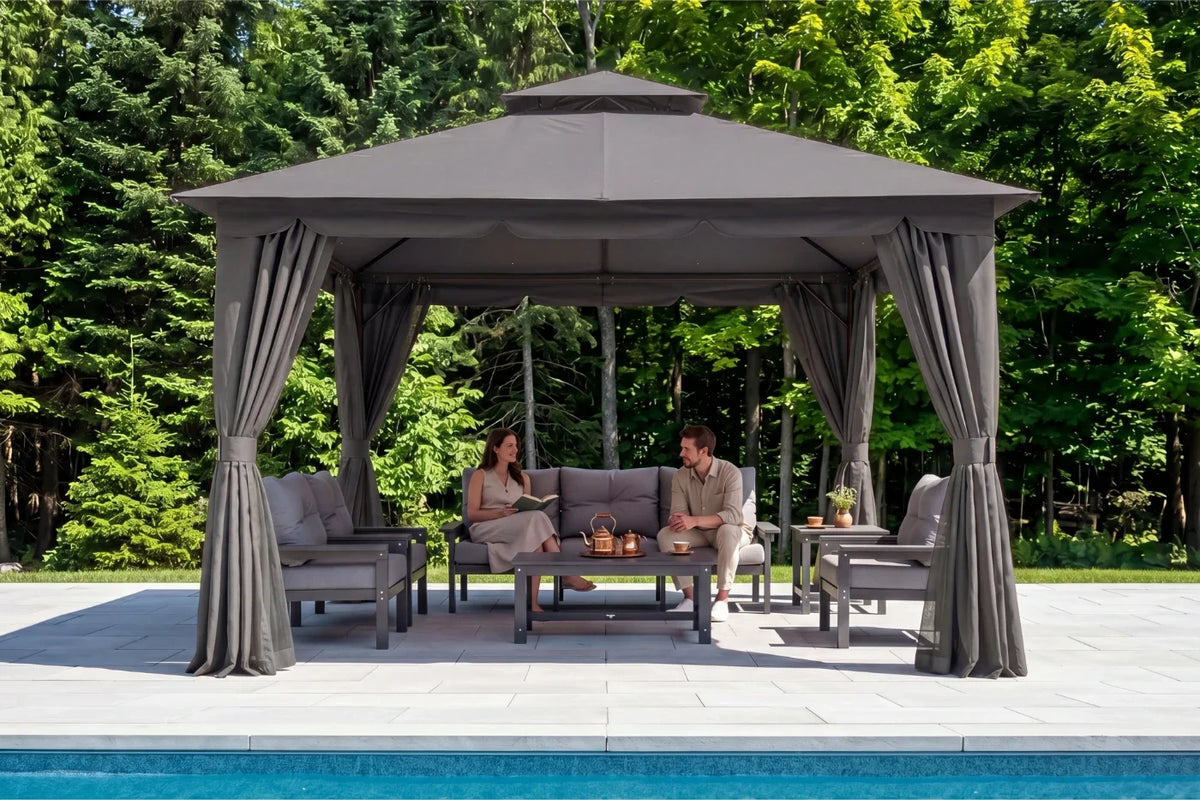 Two people sitting under a gray gazebo by a pool with trees in the background