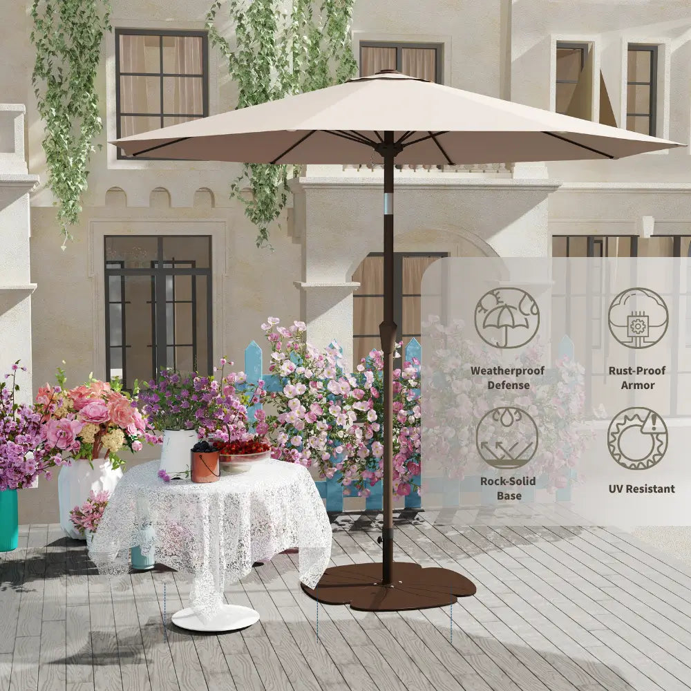 Beige patio umbrella on a wooden deck with flowers and a building in the background